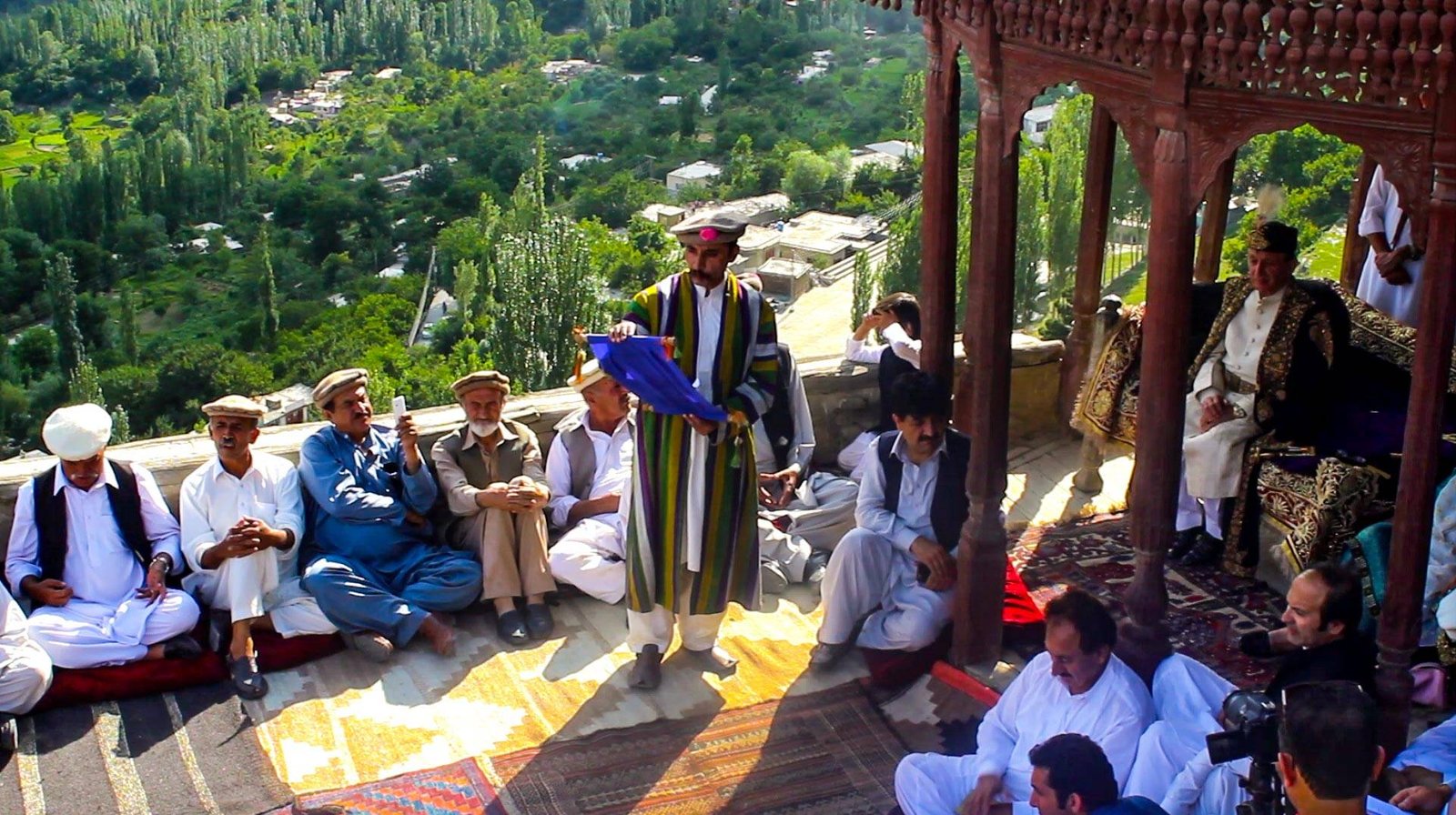 Elders and a local dignitary in traditional dress at a cultural gathering overlooking Hunza valley